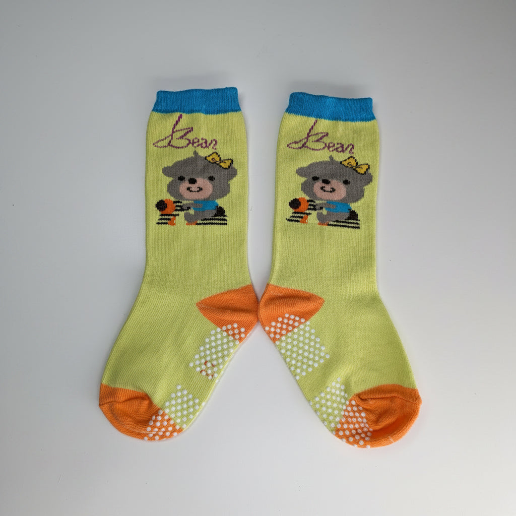 A pair of lime green baby socks with grip dots, featuring cartoon bear graphics, the name 'Jason' in purple script, and orange, blue, and white accents.
