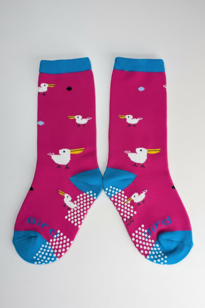 A pair of bright pink crew socks with blue heels, toes, and cuffs, featuring a white cartoon bird pattern with yellow beaks and white polka-dot heel sections. The word 'bird' is printed in blue along the sole of one sock, set against a plain light gray background.